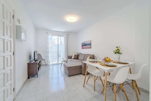 Open-Concept Living Area with a Dining Table, Sofa-Bed, AC and Smart TV.
