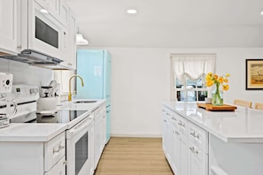 Kitchen: Whip up culinary delights in our stylish and fully equipped kitchen, boasting sleek countertops, modern appliances including a panel-ready fridge, and a spacious island with seating for gathering.
