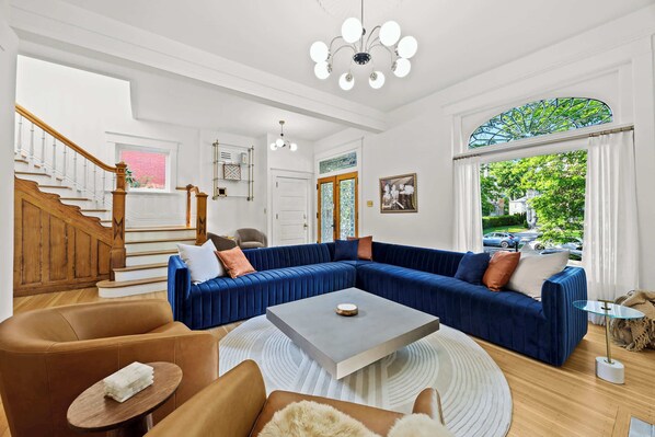 Living Room: Indulge in the vibrant elegance of our spacious living room, featuring a plush, oversized blue velvet sectional perfect for relaxing after exploring the city's charm.