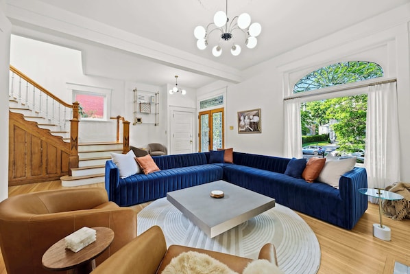 Living Room: Indulge in the vibrant elegance of our spacious living room, featuring a plush, oversized blue velvet sectional perfect for relaxing after exploring the city's charm.