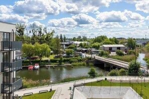 A scenic view of an apartment with modern apartment buildings, green spaces, and a river.