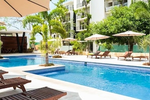The communal garden-surrounded pool with loungers