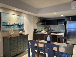Step into a beautifully designed kitchen and dining area, perfect for enjoying meals and creating memories. The modern, open layout is complemented by stylish decor, featuring nautical artwork and a charming dining space for four. 