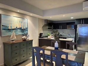 Step into a beautifully designed kitchen and dining area, perfect for enjoying meals and creating memories. The modern, open layout is complemented by stylish decor, featuring nautical artwork and a charming dining space for four.