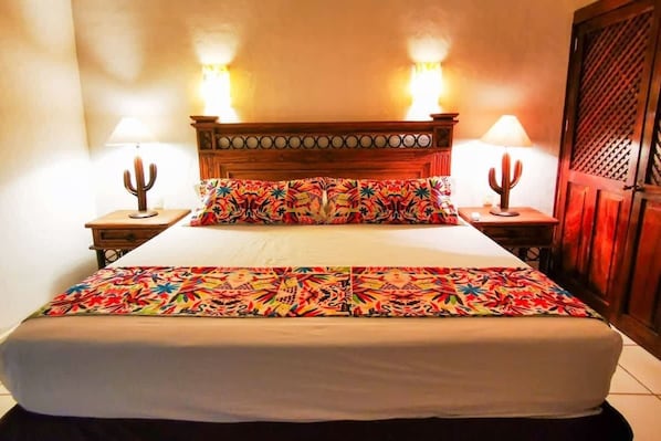Master bedroom with a king bed, Smart TV, Soft bedside lighting, direct access to bathroom, view of the gardens.
