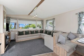 Cozy and spacious lounge with a large sofa, TV, and panoramic windows—perfect for unwinding and enjoying the view.