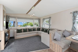 Cozy and spacious lounge with a large sofa, TV, and panoramic windows—perfect for unwinding and enjoying the view.