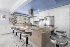 Fully equipped indoor kitchen with stainless steel appliances, island seating for 6, and dining space for 8—ideal for family meals and entertaining.