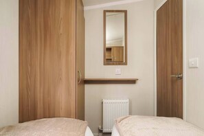 Unwind in this cozy twin room featuring plush bedding, a spacious wardrobe, and a stylish vanity—perfect for a restful and refreshing retreat.
