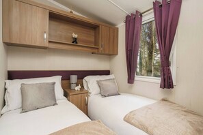 Relax in this bright twin bedroom featuring cozy beds, soft linens, and peaceful woodland views—ideal for a restful stay.