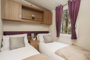 Relax in this bright twin bedroom featuring cozy beds, soft linens, and peaceful woodland views—ideal for a restful stay.