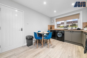 A stylish and modern kitchen with a sleek design, featuring neutral-toned cabinets, warm wood accents, and a dining area with vibrant blue chairs. A perfect space for cooking and enjoying meals together.