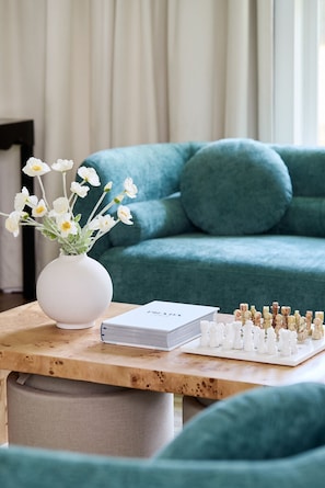 Designer coffee table with flowers, chessboard, and stylish books in Raleigh luxury Airbnb living room—perfect for games and gatherings.