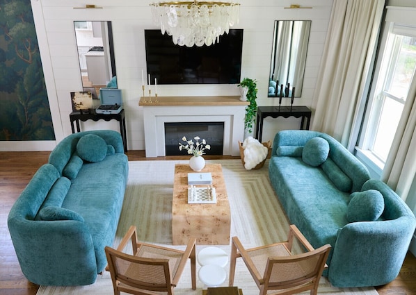 Designer living room with plush velvet sofas, a cozy fireplace, and curated textures — the perfect space to relax, connect, and unwind in your luxury Raleigh Airbnb.
