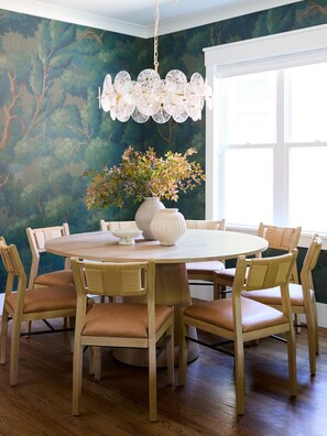 Beneath a sculptural chandelier and surrounded by whimsical forest wallpaper, your crew can gather around the round table for meals, games, or late-night takeout. It’s elegant yet grounded — a setting that invites laughter, storytelling, and second helpin