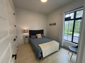 primary bedroom with large window overlooking trees and lake