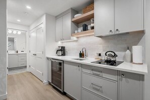Kitchenette with a mini fridge, drip coffee maker and a stove top.