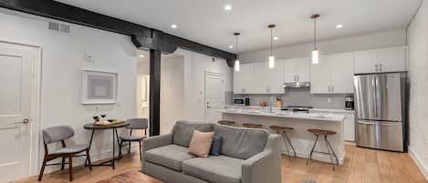 Living room with open-concept design featuring a white brick wall, Smart TV, and comfy sleeper sofa—ideal for lounging or accommodating extra guests.