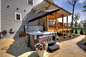 Backyard hot tub nestled among the trees with a large overhanging umbrella for shade—relax in comfort and privacy after a day exploring Ellijay’s hiking trails or apple farms. A perfect addition to this pet-friendly North Georgia Mountain cabin rental
