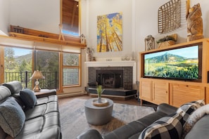 The living room features a wood burning fireplace, large smartTV, ample seating, and access to the private balcony.