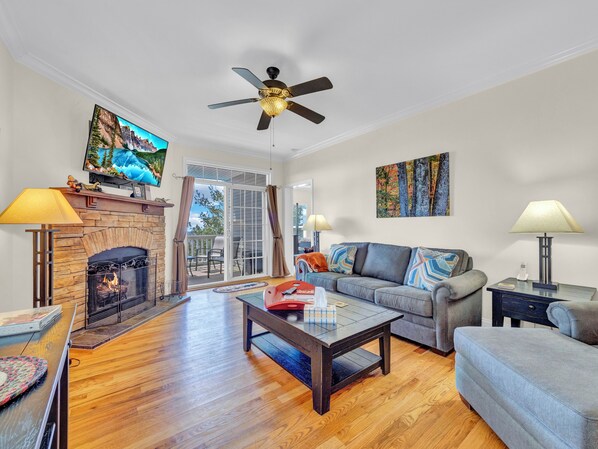 Cozy living space with stone fireplace, flat-screen TV, and direct access to the covered deck.