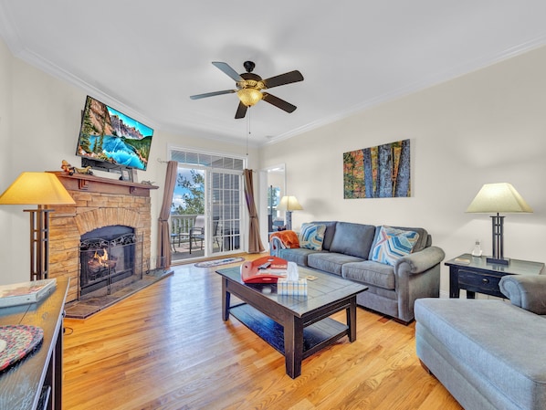 Cozy living space with stone fireplace, flat-screen TV, and direct access to the covered deck.