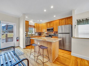 Fully equipped kitchen with stainless steel appliances, granite countertops, and bar seating.