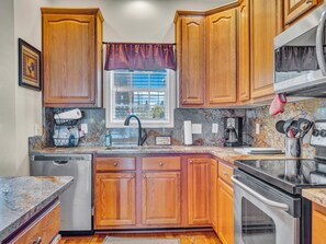 Bright kitchen corner with window above sink, granite counters, and full appliance setup.