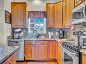 Bright kitchen corner with window above sink, granite counters, and full appliance setup.
