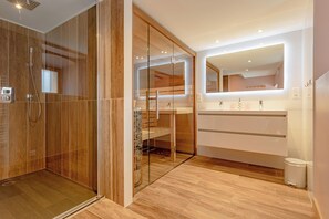 Relaxation area with private sauna, modern shower and double sink, for optimal comfort.