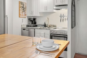Kitchen with stainless appliances, drop-leaf counter, and full dining set.