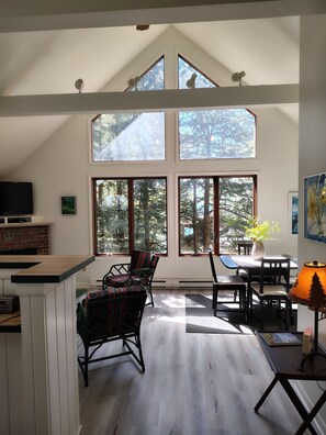View from hallway to LR/DR area with views of the woods and lake