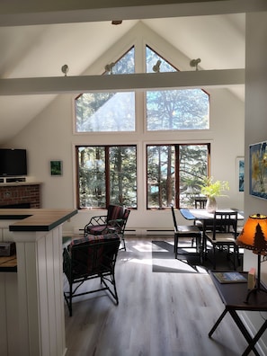 View from hallway to LR/DR area with views of the woods and lake