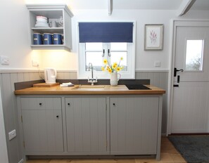 The kitchen area has a a sink, electric hob, microwave, kettle, toaster and fridge.