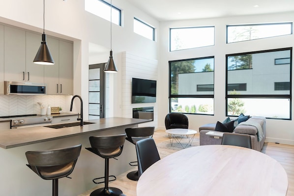A modern, minimalist dining area with ample natural light, offering a cozy setting ideal for shared meals and casual gatherings.