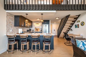 NAP-C43 This modern kitchen features sleek dark cabinetry, pendant lighting, and a brick backsplash that adds rustic charm