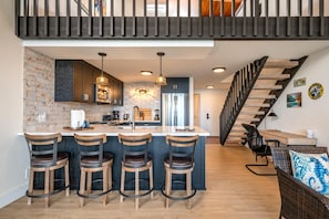 NAP-C43 This modern kitchen features sleek dark cabinetry, pendant lighting, and a brick backsplash that adds rustic charm