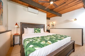 NAP-C43 Elegant loft-style master with king bed, island artwork, exposed beams, and soft light from balcony rail views