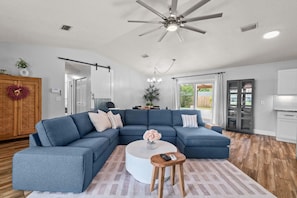 Spacious living room with a large sectional, Smart TV, and open floorplan — sliding doors lead straight to your private outdoor oasis.