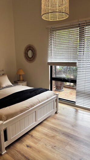 Sunlit large bedroom with queen bed and robe.