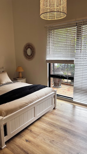 Sunlit large bedroom with queen bed and robe.