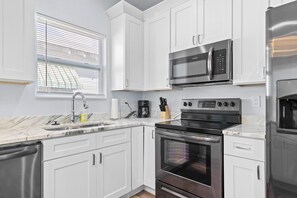 Fully stocked kitchen with sleek appliances and countertop dining, ideal for cooking and dining in comfort.