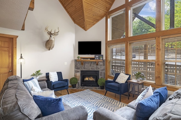 Relax in the spacious living room of this retreat, where natural light floods through wide windows, highlighting high ceilings and comfortable seating. Ideal for unwinding after a day of exploring Table Rock Lake and the Ozark Mountains in Branson, MO.