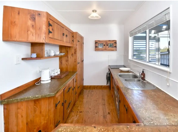 Bespoke cottage kitchen with dishwasher and window opening to deck
