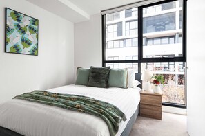 A master bedroom with a queen sized bed & plush pillows.