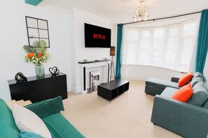 Grey L shape three seater sofa bed, smart TV, coffee table, tall lamp & cabinet