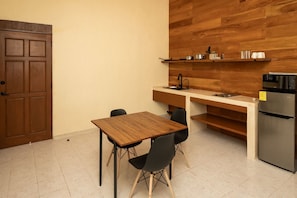 Cocina equipada con estufa, refrigerador, microondas, cafetera francesa y barra comedor. Cuenta con aire acondicionado, ventilador de techo, dos amplias ventanas para ventilación cruzada, vista a jardín interior y luces dimerizables para crear el ambiente perfecto.