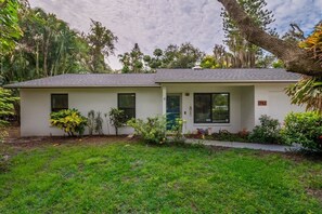 Peaceful home tucked in lush greenery with a private screened pool, covered patio lounge, and spacious driveway