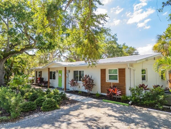 One-story home surrounded by lush tropical landscaping, shaded walkways, and mature trees.