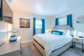 This bedroom features a comfortable queen bed, two modern nightstands with lamps, a flat-screen TV, dresser, and built-in closet. Easy access to shared spaces from this bedroom.
